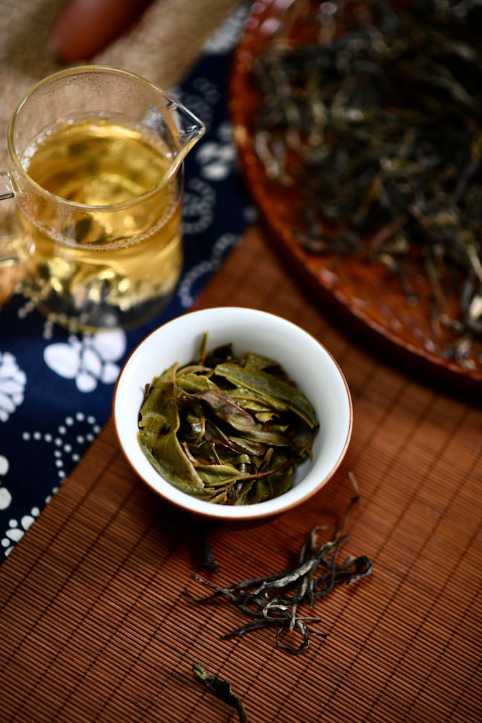 client-stories-img High angle view of freshly brewed tea with loose leaves on a bamboo mat, showcasing traditional tea preparation.
